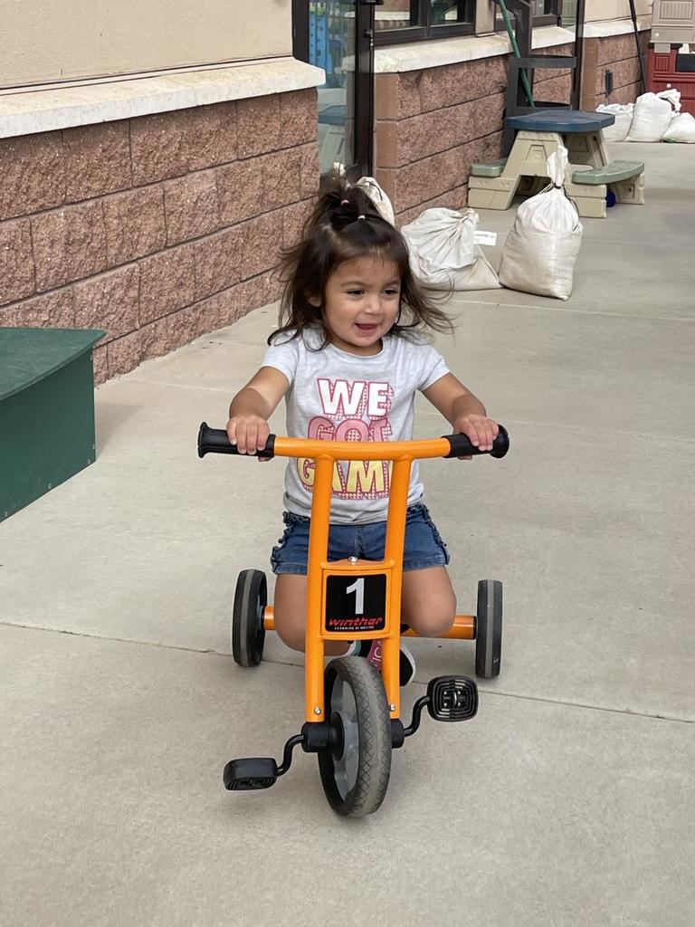 Toddler girl riding tricycle outside